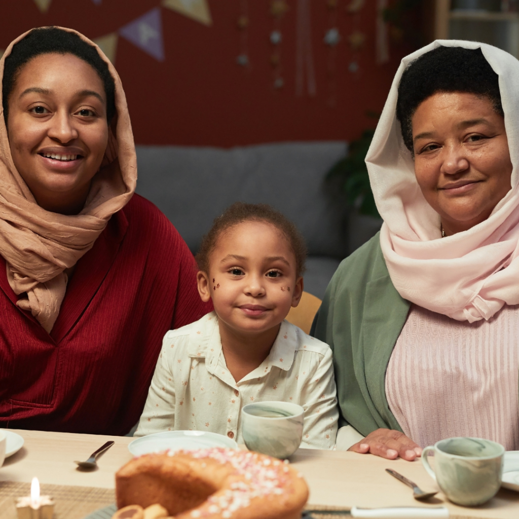 A child sits in between 2 women in hijabs.