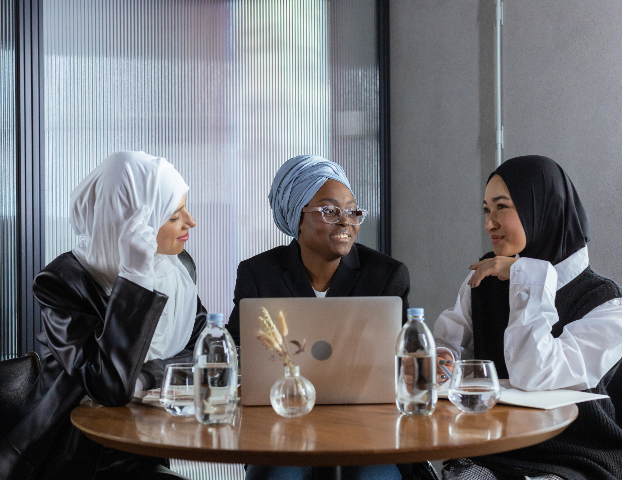 3 women chatting while sitting in front of a laptop