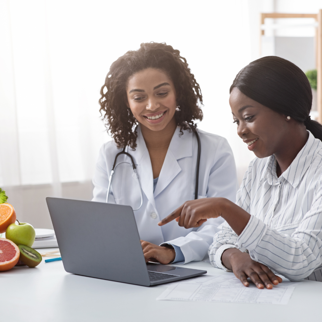 A female doctor and a woman look over a laptop.